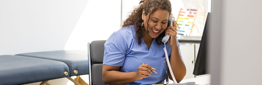 Smiling healthcare worker talking on phone at office stock photo
