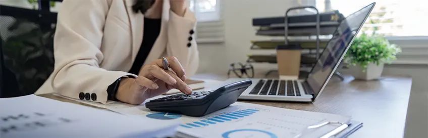Businesswoman accountant using calculator and laptop for matching financial data saving in office room